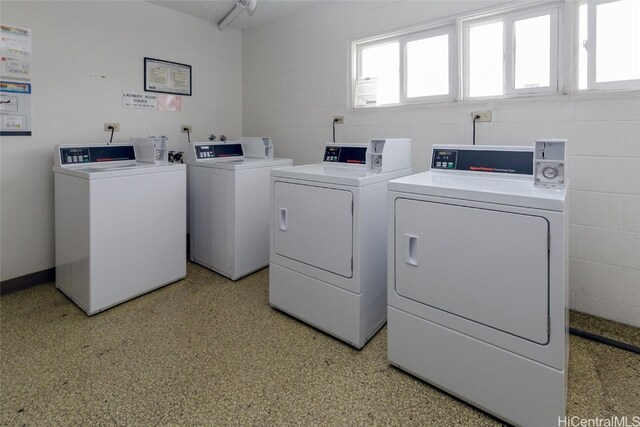 shared laundry area with concrete block wall and separate washer and dryer