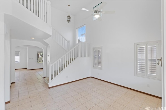 interior space with plenty of natural light, ceiling fan, and a towering ceiling