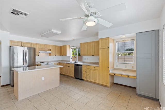 kitchen with stainless steel appliances, a kitchen island, a healthy amount of sunlight, and sink