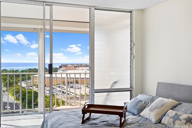 bedroom featuring a water view, multiple windows, and a wall of windows