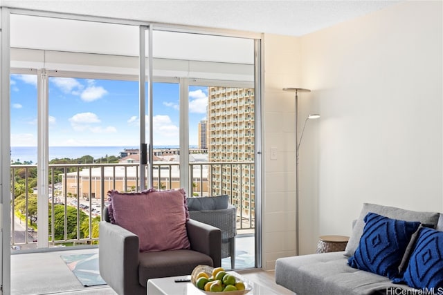 living room featuring a water view, a textured ceiling, a wall of windows, and plenty of natural light