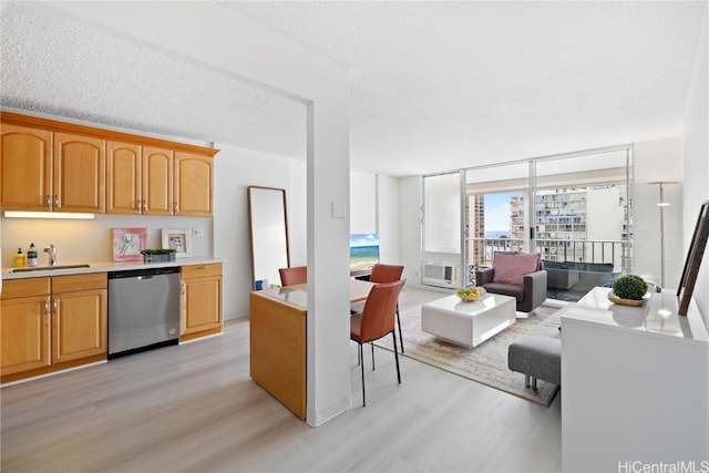 kitchen featuring a textured ceiling, floor to ceiling windows, light hardwood / wood-style flooring, dishwasher, and sink