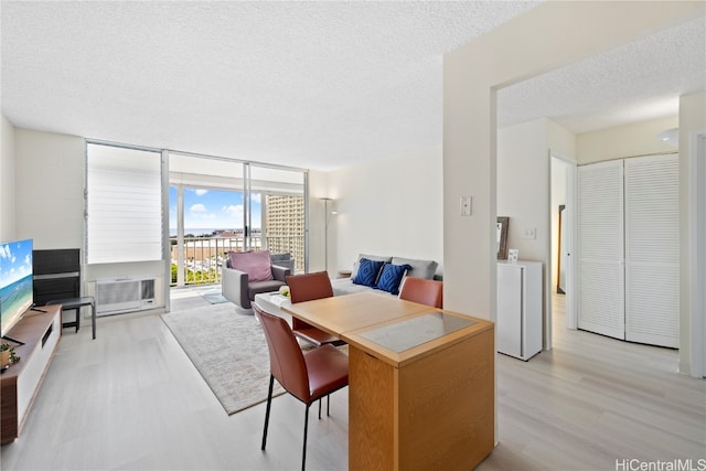 dining area with light hardwood / wood-style flooring, cooling unit, a textured ceiling, and floor to ceiling windows