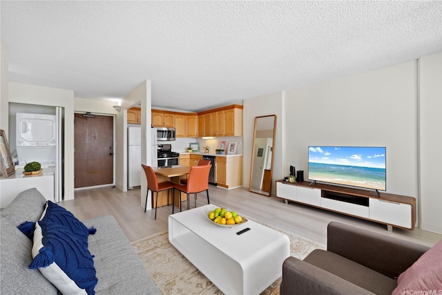 475 Atkinson Dr Unit 1702, Honolulu, HI 96814 - living room featuring estacked washer and dryer, light wood finished floors, and a textured ceiling