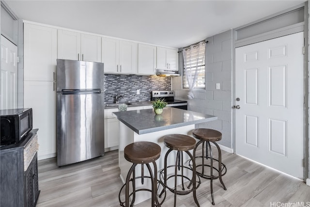 kitchen featuring white cabinetry, appliances with stainless steel finishes, light hardwood / wood-style floors, and a kitchen breakfast bar