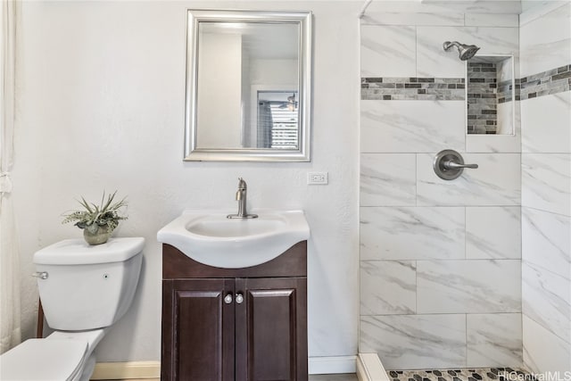 bathroom with a tile shower, vanity, and toilet