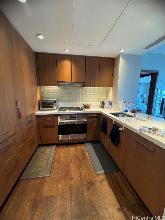 kitchen featuring sink, stainless steel appliances, backsplash, and hardwood / wood-style flooring