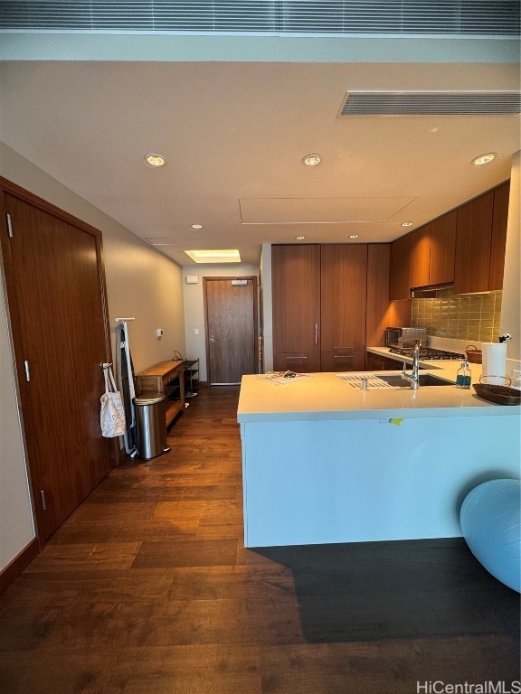 kitchen featuring sink, backsplash, dark hardwood / wood-style flooring, and kitchen peninsula