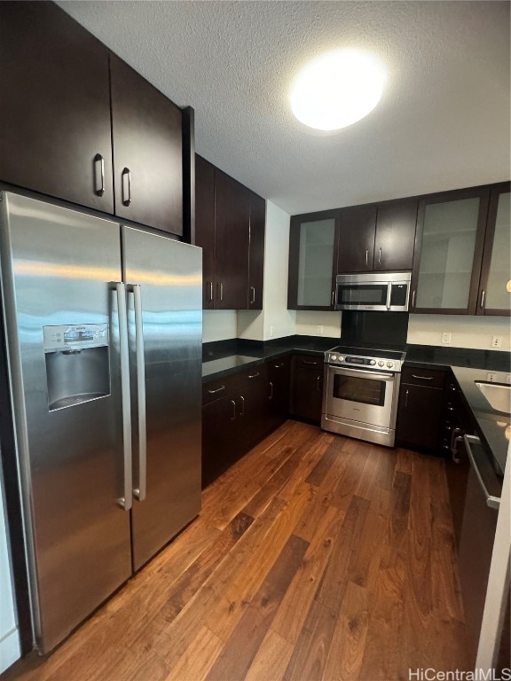 kitchen with dark hardwood / wood-style flooring, a textured ceiling, sink, dark brown cabinetry, and stainless steel appliances