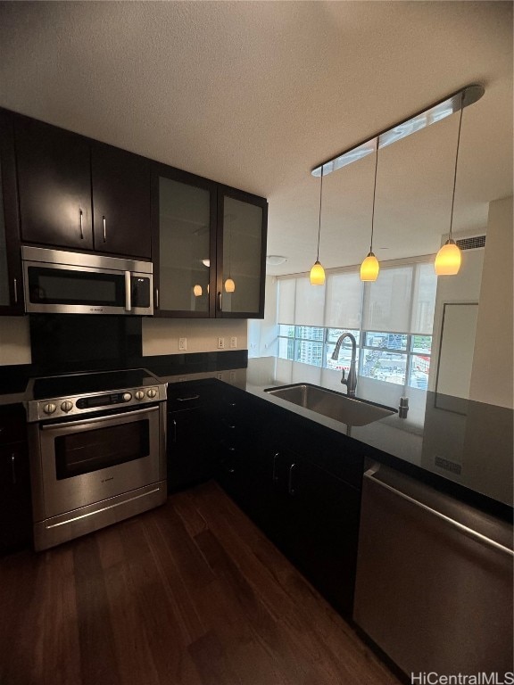 kitchen featuring dark hardwood / wood-style flooring, appliances with stainless steel finishes, a textured ceiling, sink, and decorative light fixtures