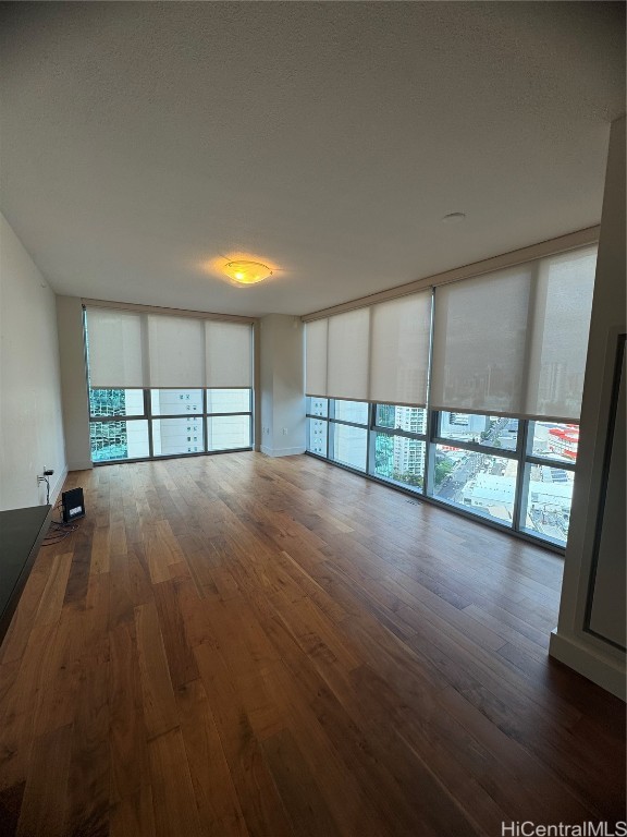 unfurnished room featuring a textured ceiling, dark wood-type flooring, and floor to ceiling windows