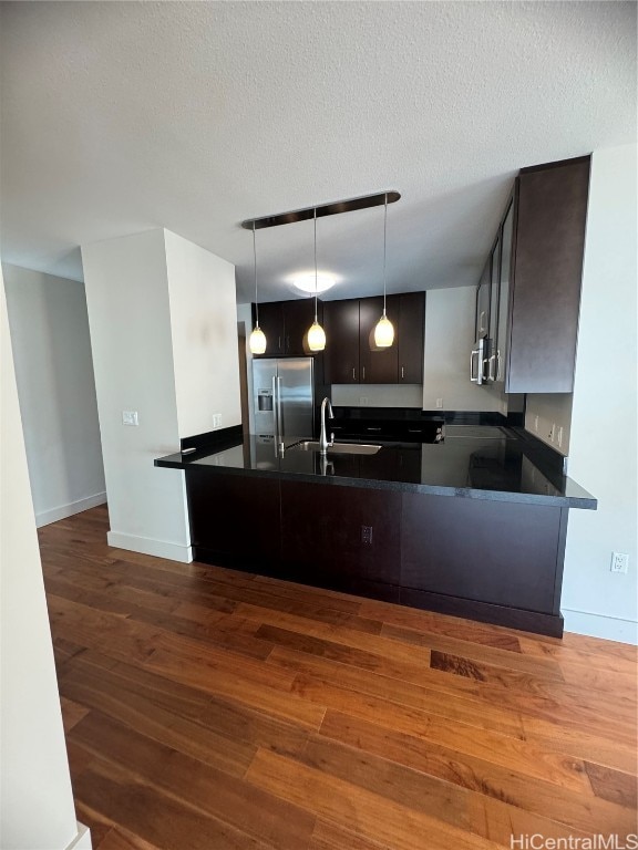 kitchen featuring stainless steel appliances, dark brown cabinets, kitchen peninsula, and dark hardwood / wood-style floors