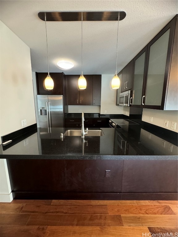 kitchen with wood-type flooring, sink, dark brown cabinetry, pendant lighting, and appliances with stainless steel finishes