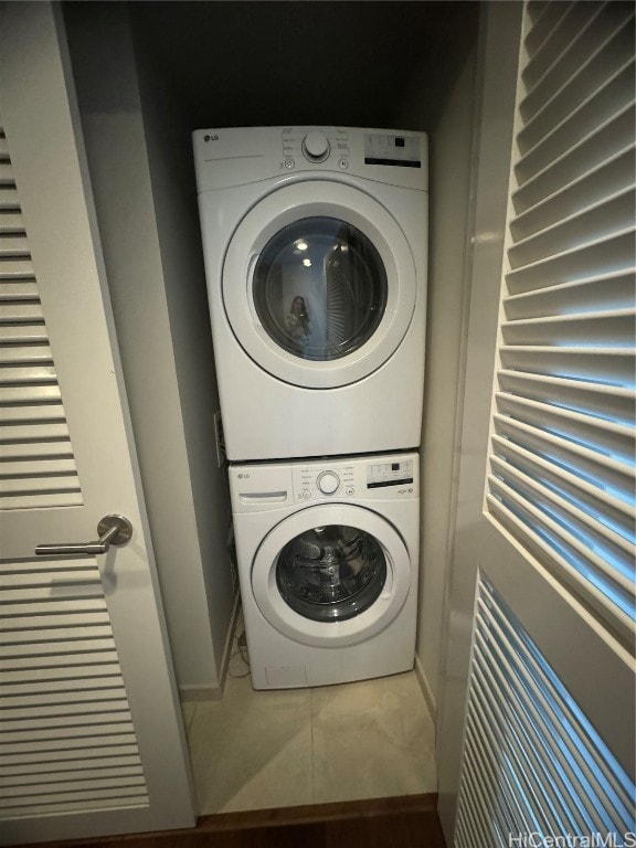 clothes washing area with tile patterned floors and stacked washer and clothes dryer