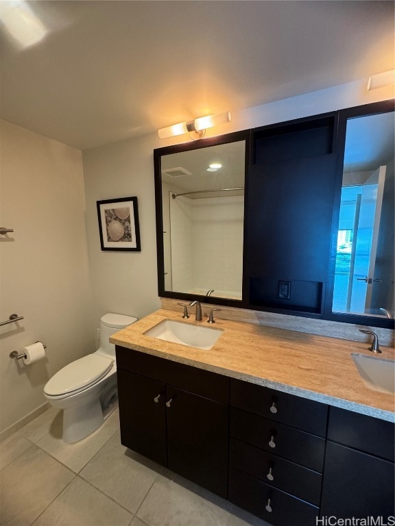 bathroom with toilet, vanity, and tile patterned floors