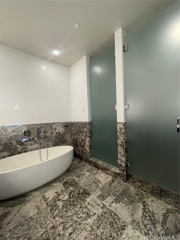 bathroom featuring tile walls, sink, and a bathtub