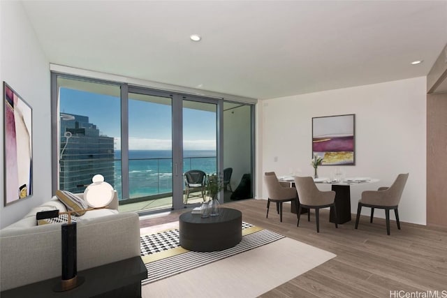 living room with a wall of windows, a water view, and hardwood / wood-style flooring