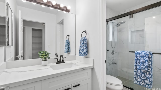 bathroom with toilet, vanity, and a shower with door