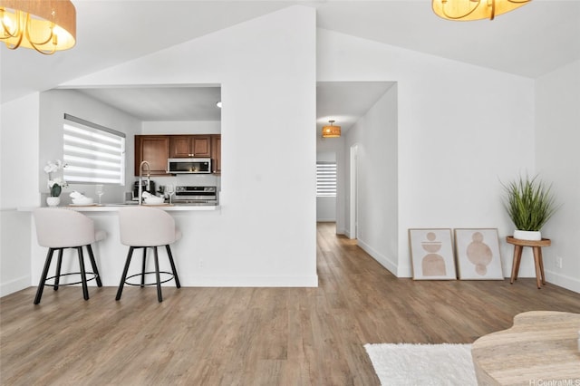 91-1030 Hoopili St Unit 54, Ewa Beach, HI 96706 - kitchen with stainless steel appliances, a kitchen bar, a chandelier, light wood finished floors, and lofted ceiling