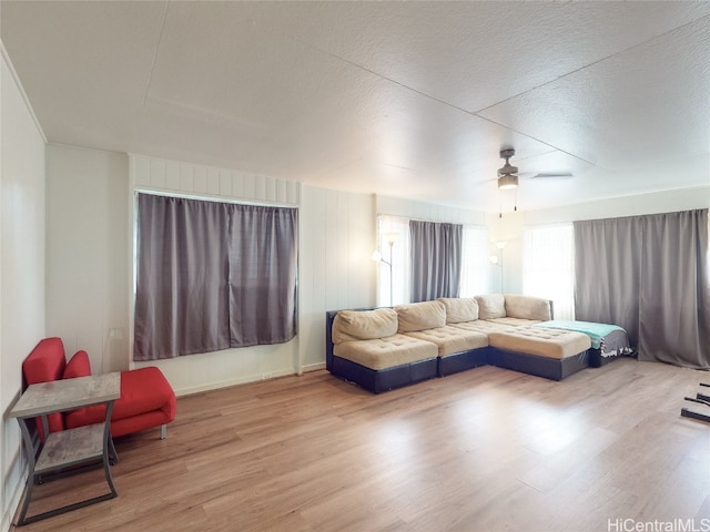 living room featuring ceiling fan, hardwood / wood-style flooring, and a textured ceiling