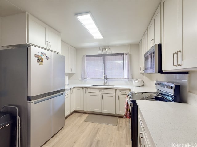 kitchen featuring sink, light hardwood / wood-style flooring, stainless steel appliances, and white cabinetry