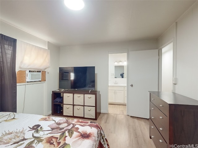 bedroom featuring ensuite bath, cooling unit, sink, and light wood-type flooring