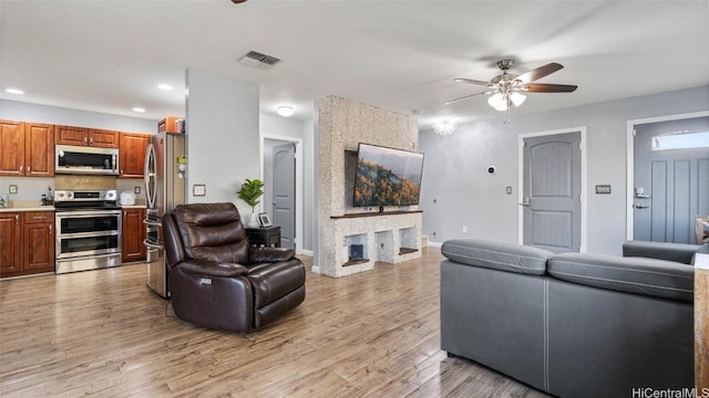 living room featuring ceiling fan and light hardwood / wood-style floors