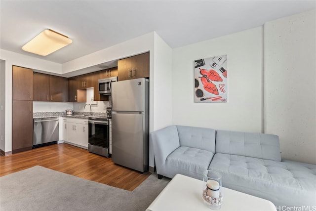 kitchen with sink, appliances with stainless steel finishes, dark brown cabinetry, and hardwood / wood-style floors