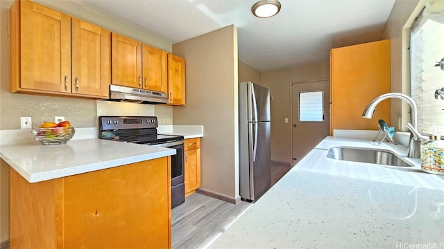 kitchen with light stone countertops, sink, light hardwood / wood-style flooring, black / electric stove, and stainless steel fridge