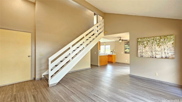 unfurnished living room with beam ceiling, light hardwood / wood-style floors, high vaulted ceiling, and ceiling fan