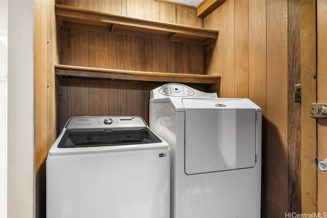 clothes washing area featuring independent washer and dryer and wooden walls