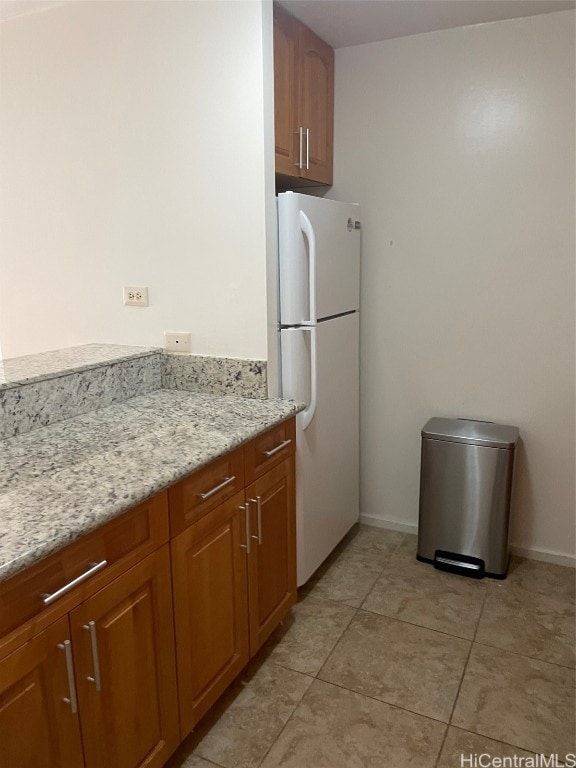 kitchen featuring light stone countertops, light tile patterned floors, and white refrigerator