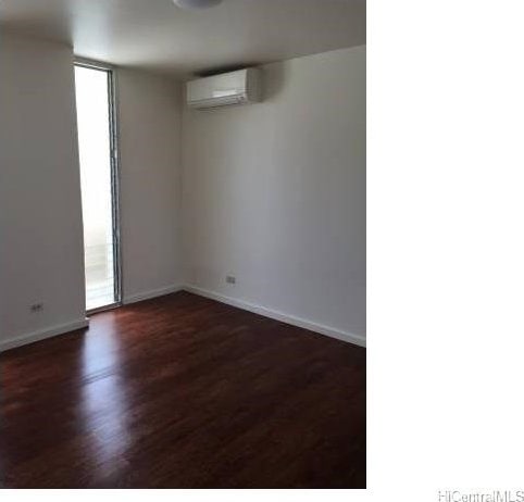 empty room with a wall mounted air conditioner and dark hardwood / wood-style floors