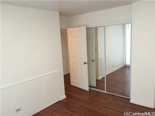 unfurnished bedroom with a closet and dark hardwood / wood-style floors