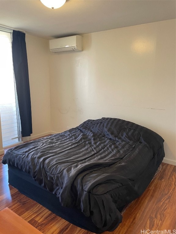 bedroom with a wall mounted AC and dark hardwood / wood-style floors