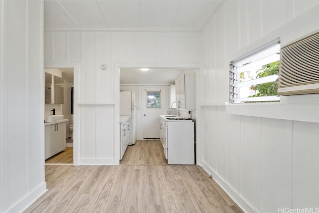 kitchen featuring sink, white cabinets, white appliances, and light wood-type flooring