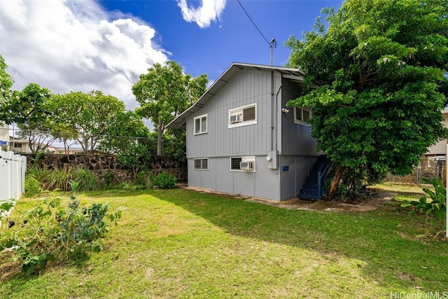 rear view of house with a lawn and an AC wall unit