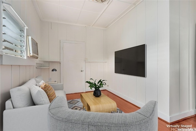 living room with a wall mounted AC, wood walls, and wood-type flooring