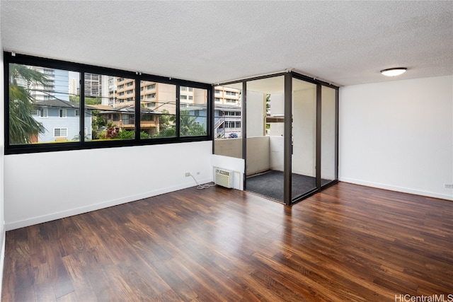 unfurnished bedroom with a textured ceiling, dark hardwood / wood-style flooring, a closet, expansive windows, and a wall unit AC