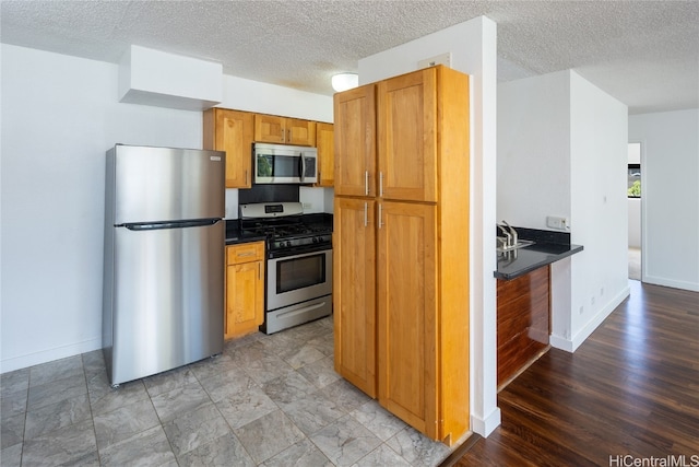 kitchen with light hardwood / wood-style flooring, a textured ceiling, and stainless steel appliances