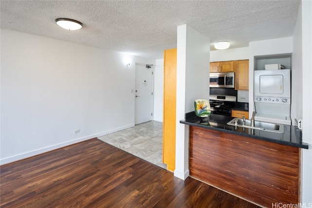 kitchen featuring light hardwood / wood-style floors, appliances with stainless steel finishes, sink, and stacked washer and clothes dryer