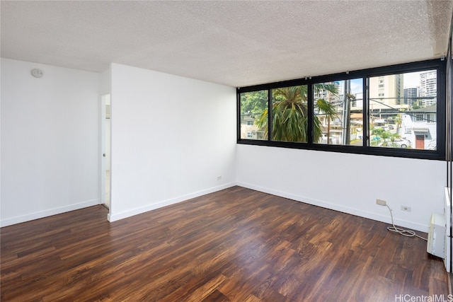 empty room featuring a textured ceiling and dark hardwood / wood-style flooring