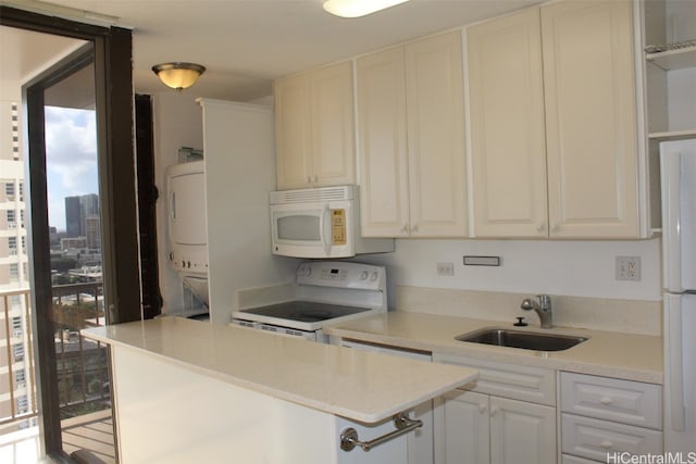 kitchen featuring sink, white cabinets, white appliances, and stacked washing maching and dryer