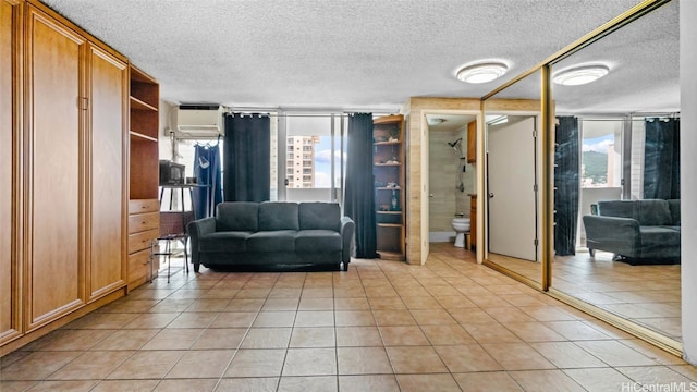 unfurnished room featuring a wall mounted air conditioner, a textured ceiling, light tile patterned flooring, and plenty of natural light