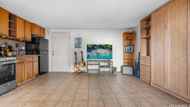 kitchen with stainless steel range oven, a textured ceiling, electric panel, light tile patterned floors, and black refrigerator