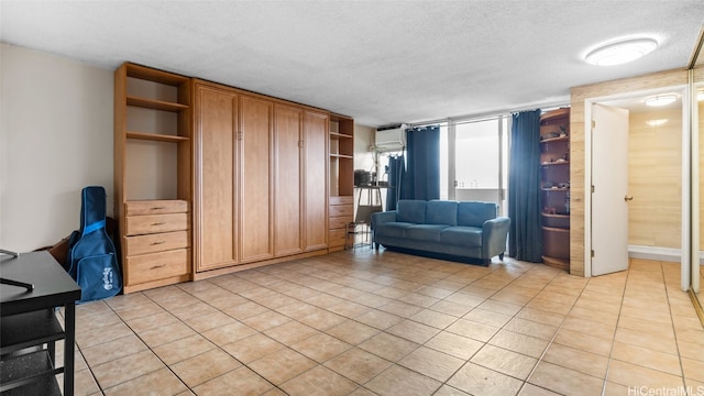 interior space with a textured ceiling, light tile patterned flooring, and an AC wall unit