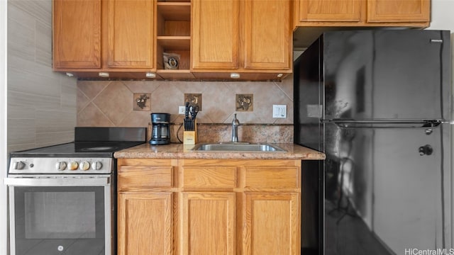 kitchen with backsplash, sink, stainless steel range with electric cooktop, and black refrigerator