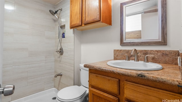 bathroom with toilet, vanity, and tiled shower