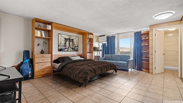 bedroom with a wall unit AC, a textured ceiling, and light tile patterned floors