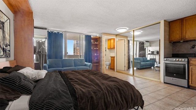 tiled bedroom featuring a closet, a textured ceiling, a wall mounted AC, and ensuite bath